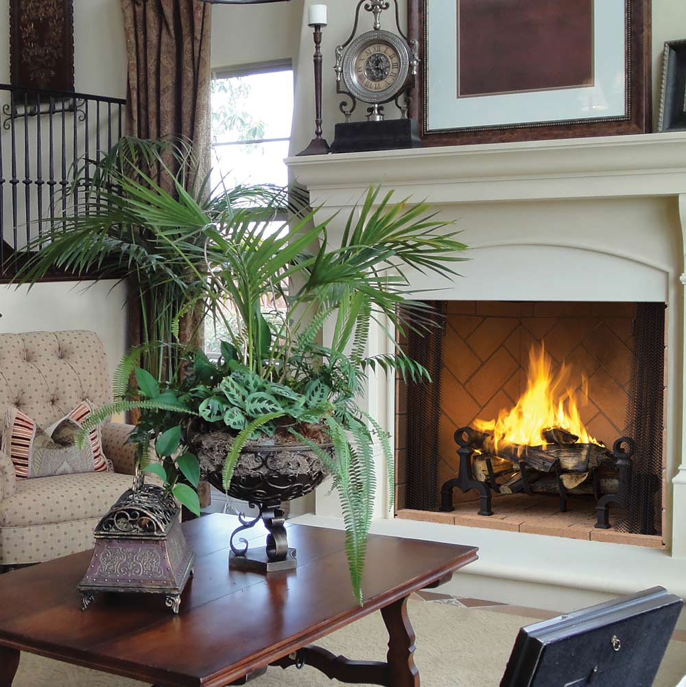 Masonry wood burning fireplace with black screen, burning logs, and mantel.