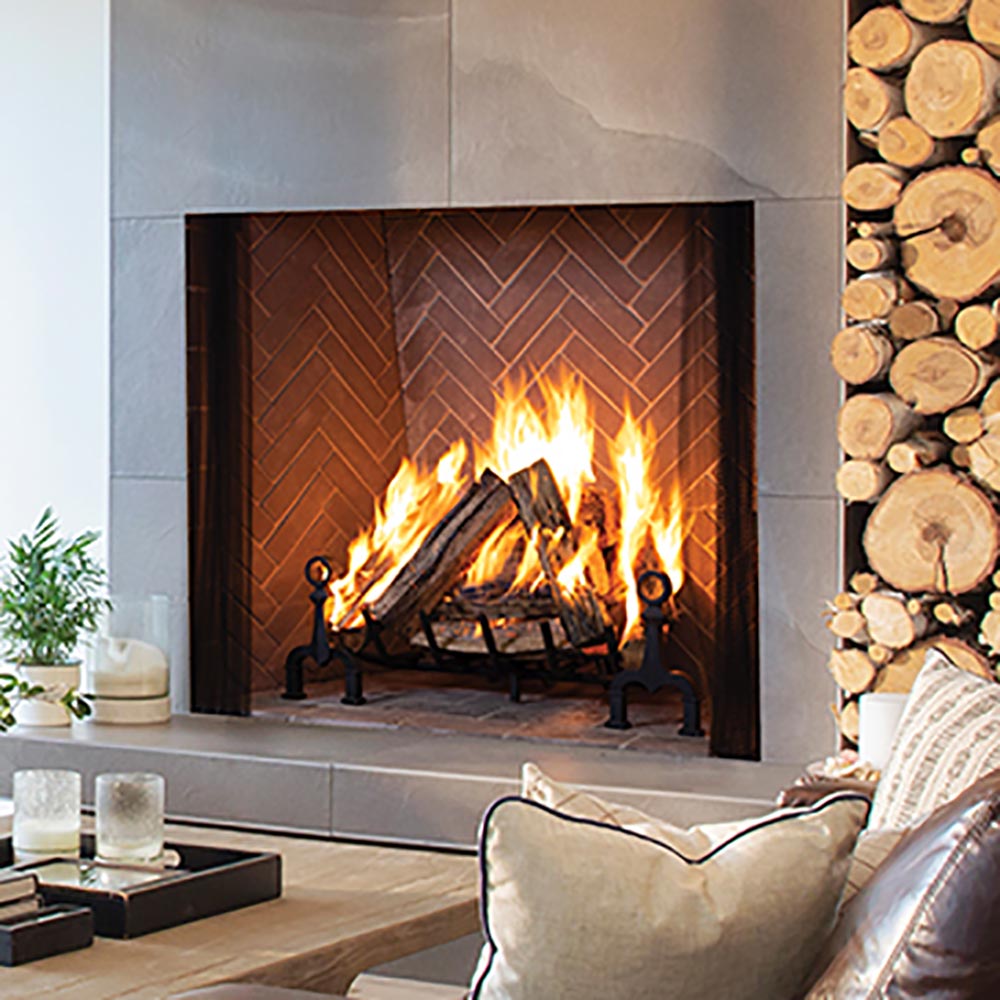 Wood-burning fireplace with warm brown split herringbone tile surround and black fireplace tools