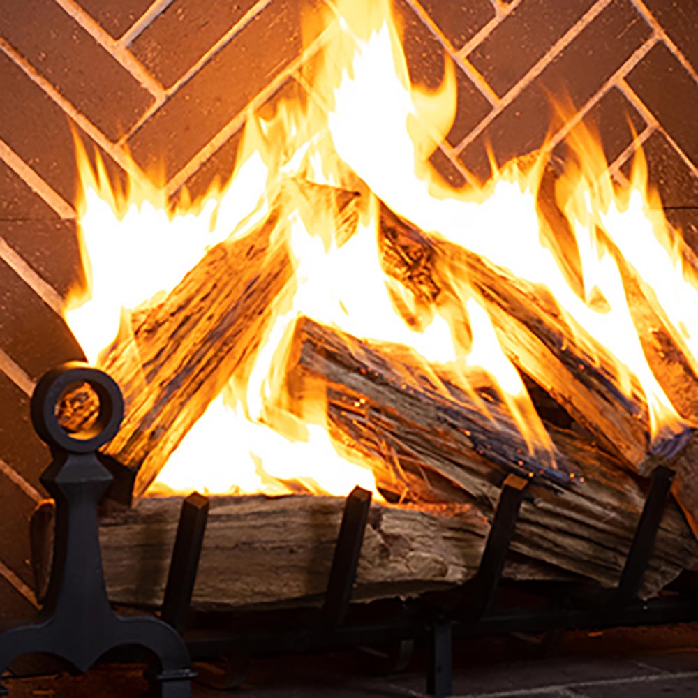 Close-up of burning wood in split herringbone masonry firebox with black tools