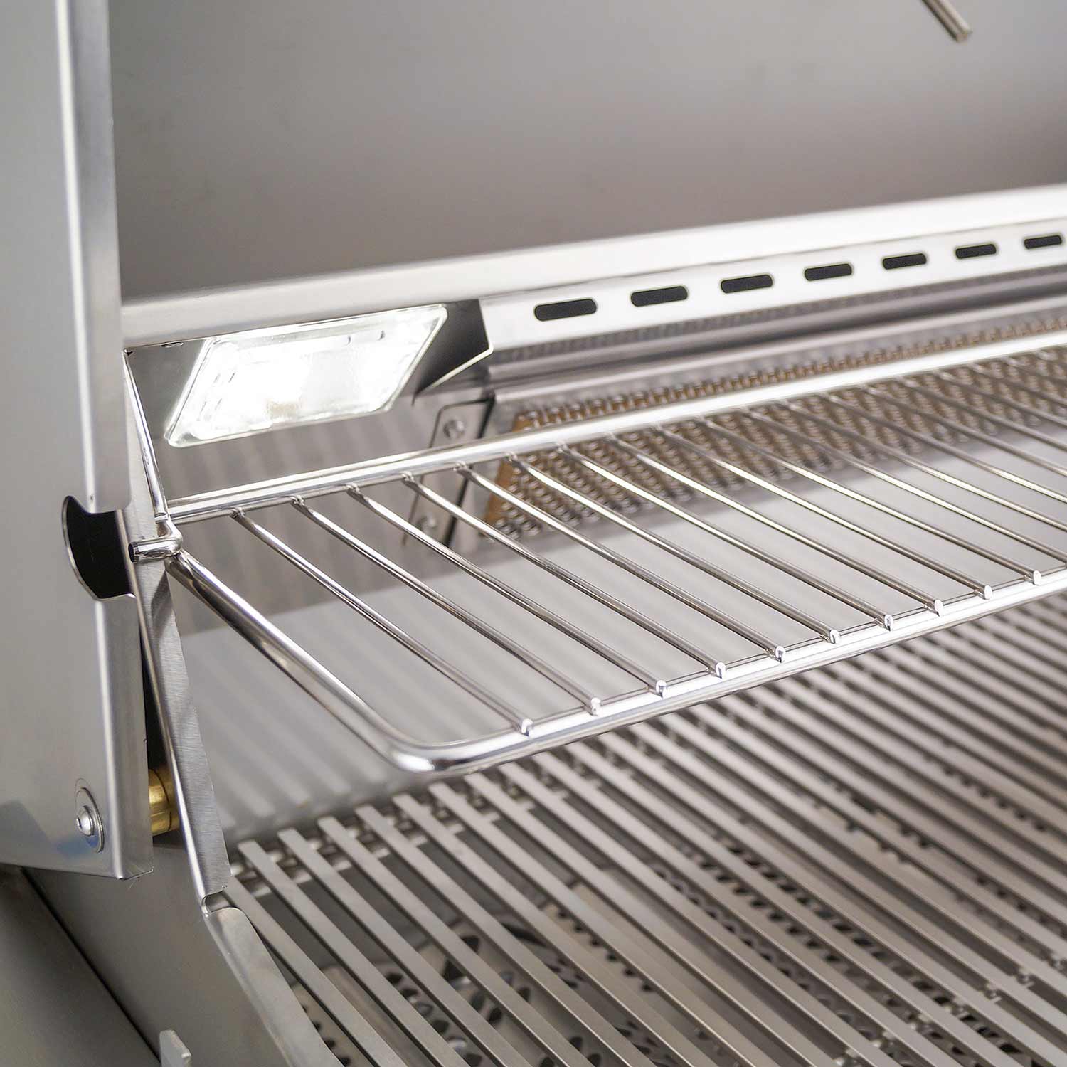 Stainless steel warming rack above the cooking grates inside a gas grill