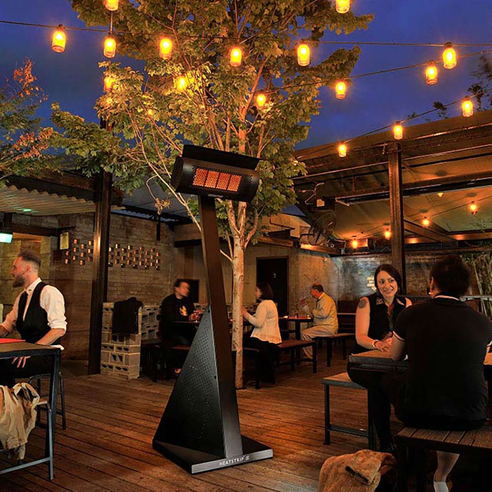 Freestanding LPG gas patio heater with glowing infrared emitter beside outdoor seating