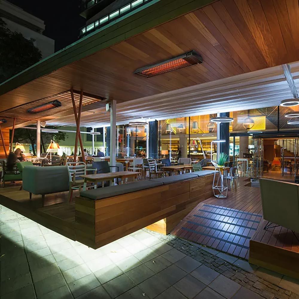Wall-mounted outdoor patio heater with glowing infrared bar under a patio roof