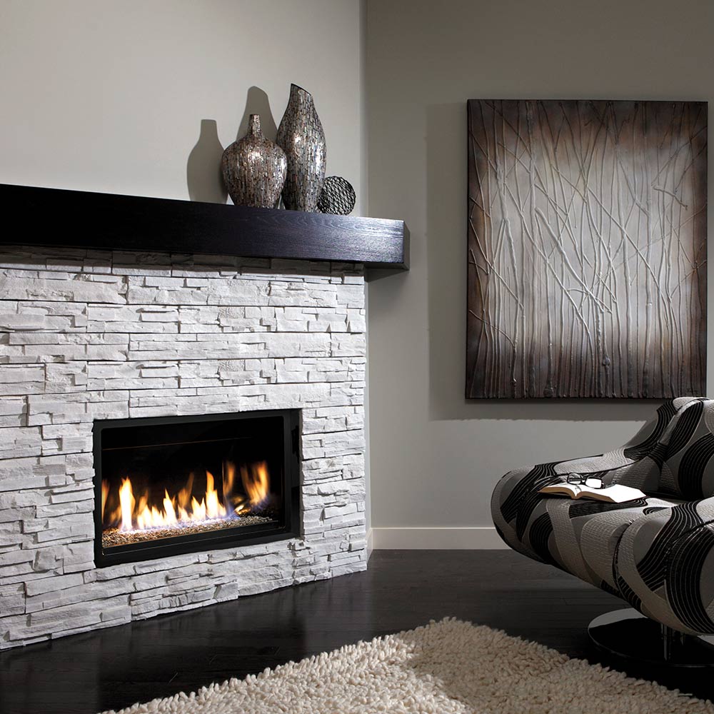 Linear direct vent gas fireplace insert with flames and fire glass in stone surround