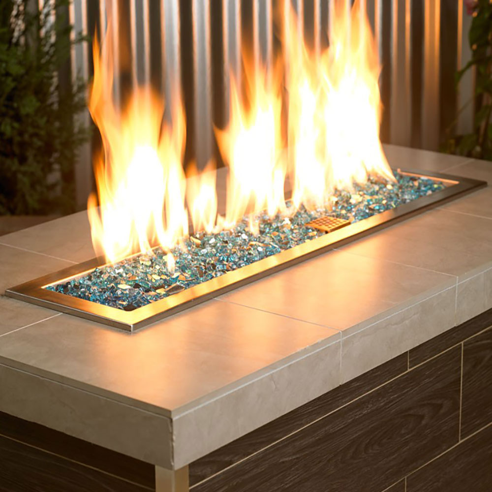Teal-blue fire glass in a rectangular fire pit with visible flames
