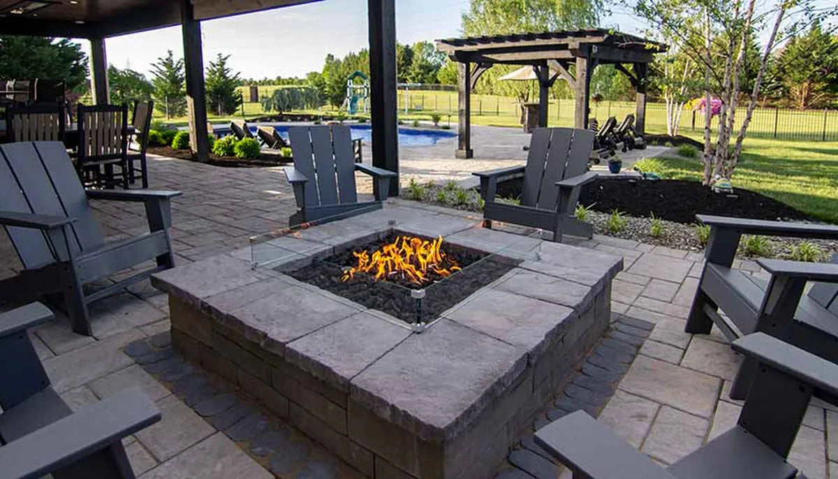 Square natural stone fire pit with stainless vent grate and lit burner — fire pit ventilation and airflow design