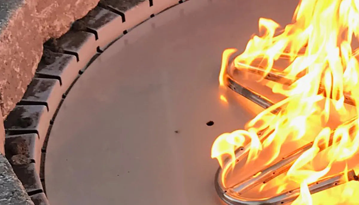 Close-up of a round fire pit installation collar and pan with active flames — fire pit installation collar and burner pan fitting
