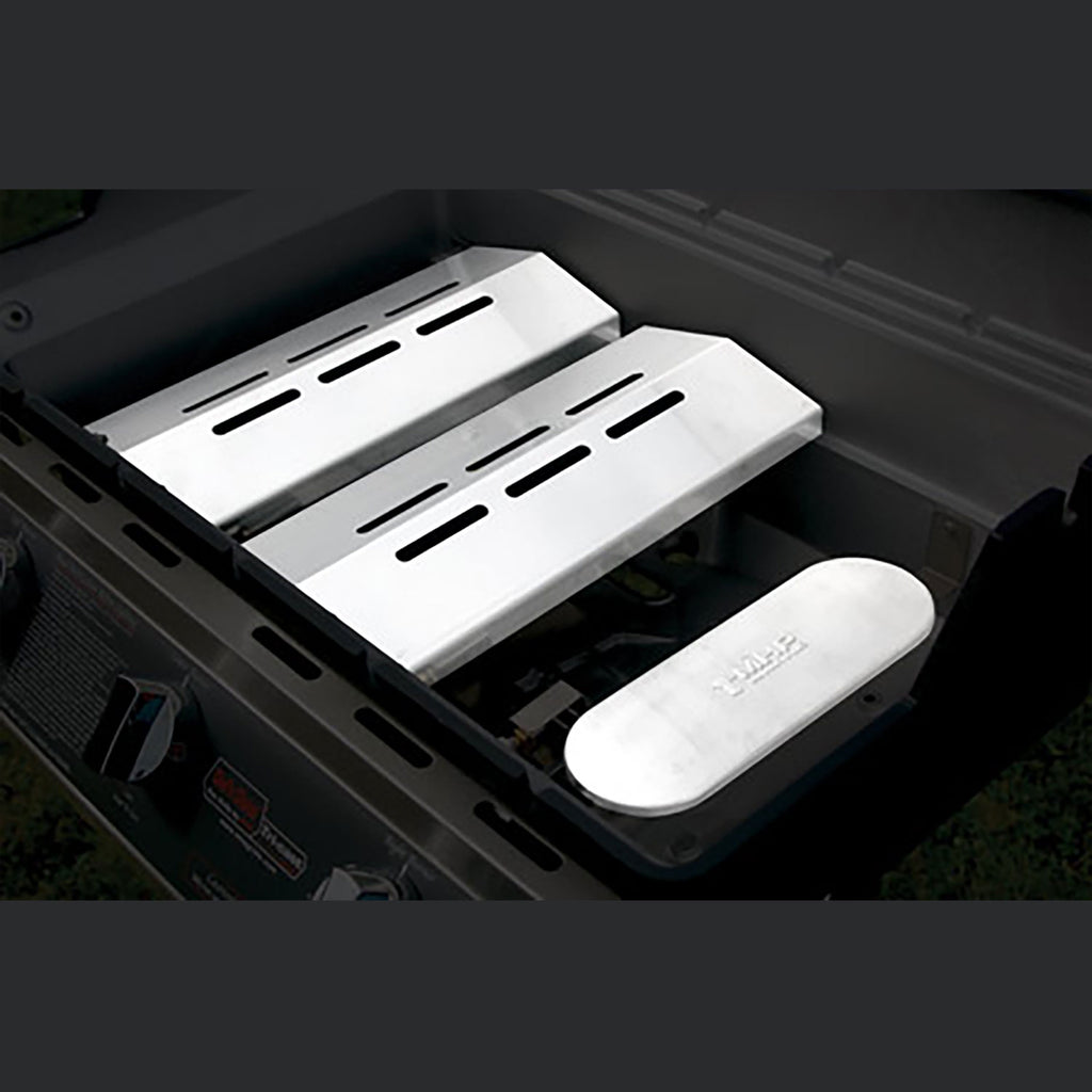 Tri-burn gas grill open lid showing SearMagic grid plates and side accessory tray
