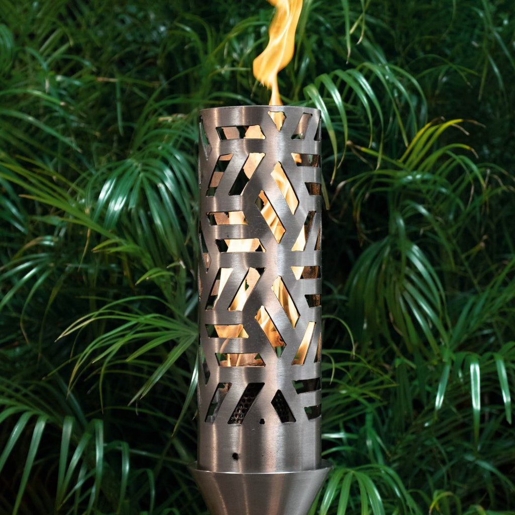 Patio torch with cutout metal cylinder, open flame burning in garden