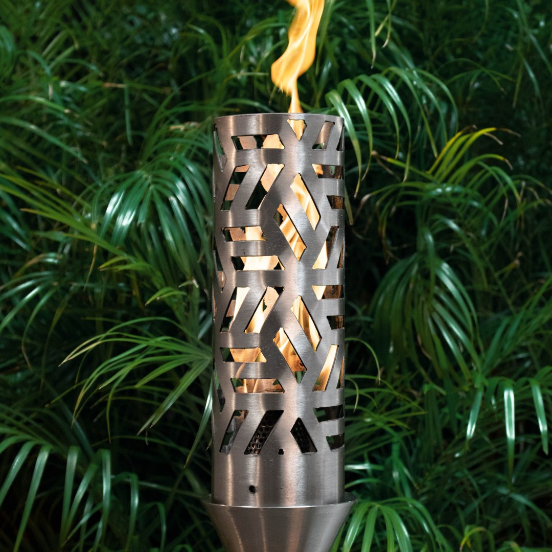 Patio torch with cutout metal cylinder, open flame burning in garden