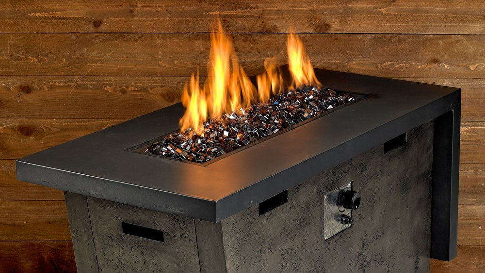 Fire pit with visible flames over fire glass cubes