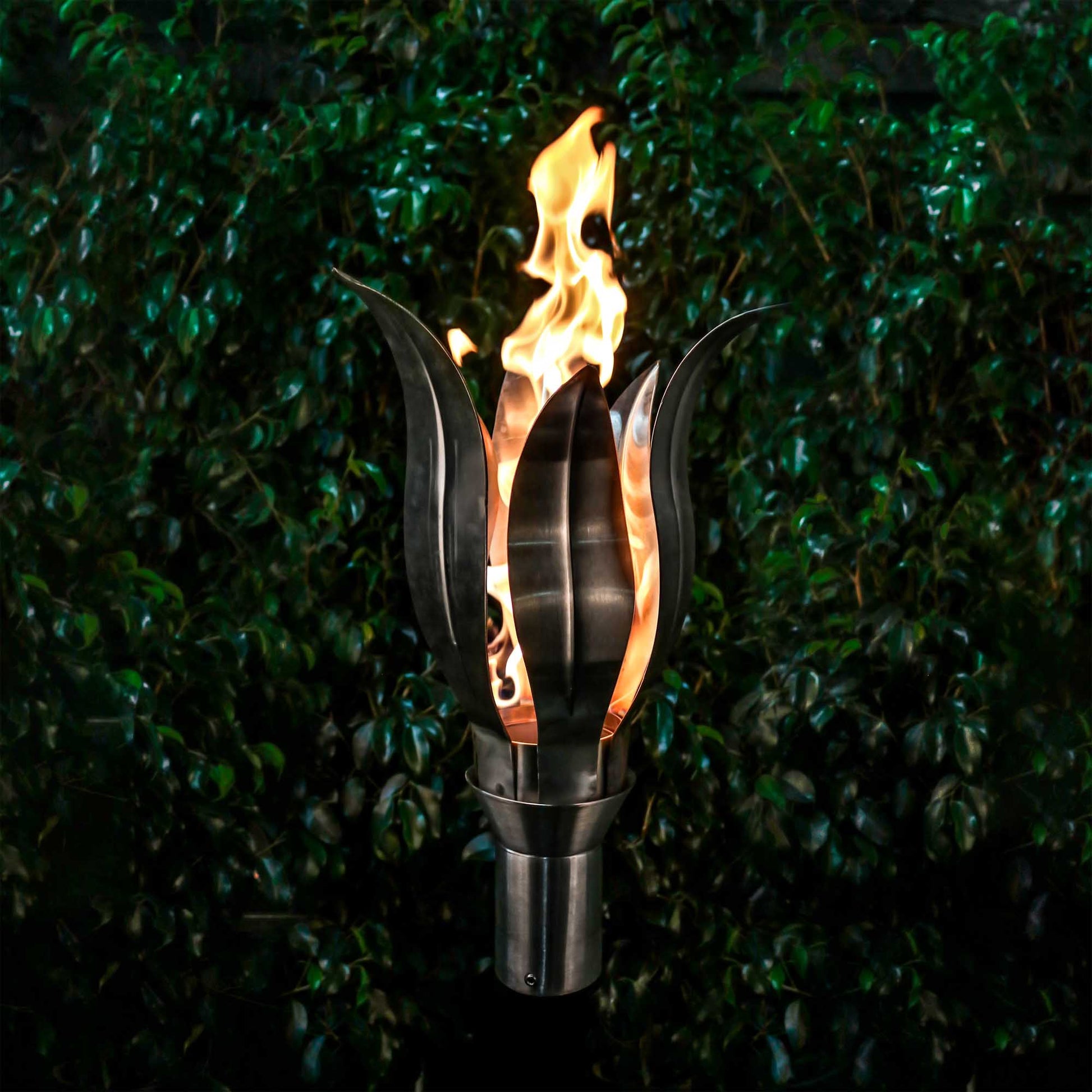 Outdoor torch with stand, burning flame rising from black metal base