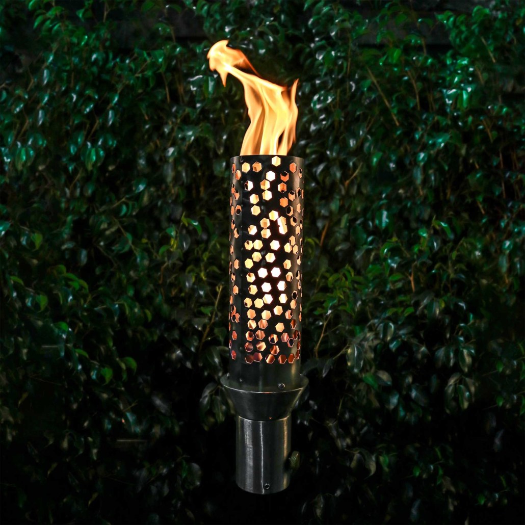 Outdoor torch with honeycomb metal body and burning flame, on dark stand base
