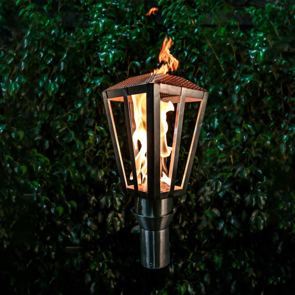 Lantern-style propane torch with metal frame and burning flame inside glass panels