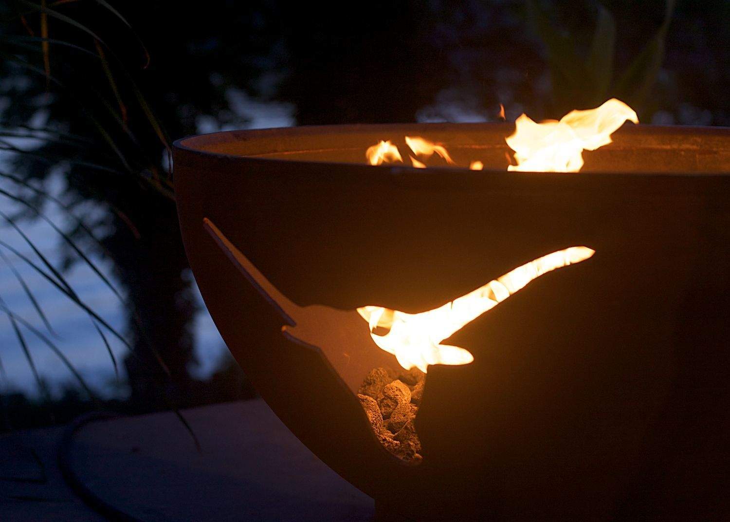 Orange-brown gas fire pit bowl with longhorn cutout and burning flame