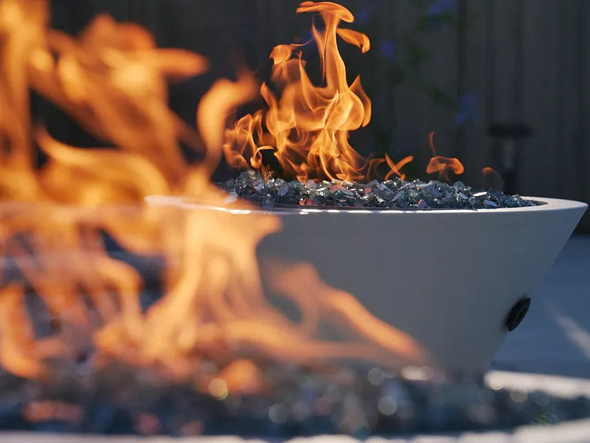 White fire pit with flames and glowing embers on a blurred background