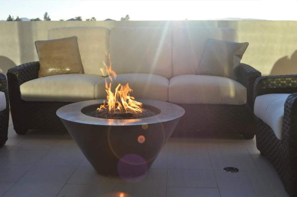Hammered copper gas fire bowl with visible flames in outdoor patio