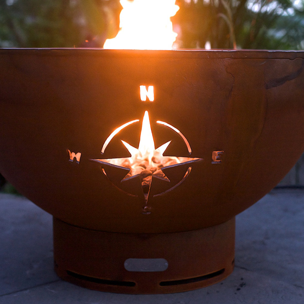 Rust gas fire pit bowl with lit burner and star compass emblem on front
