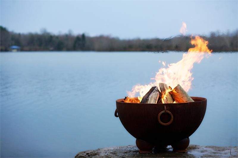 Gas fire pit bowl with flames and circular side air port, logs inside
