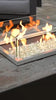 Closeup of a gas flame in a linear rustic fire pit with a windguard and fire glass
