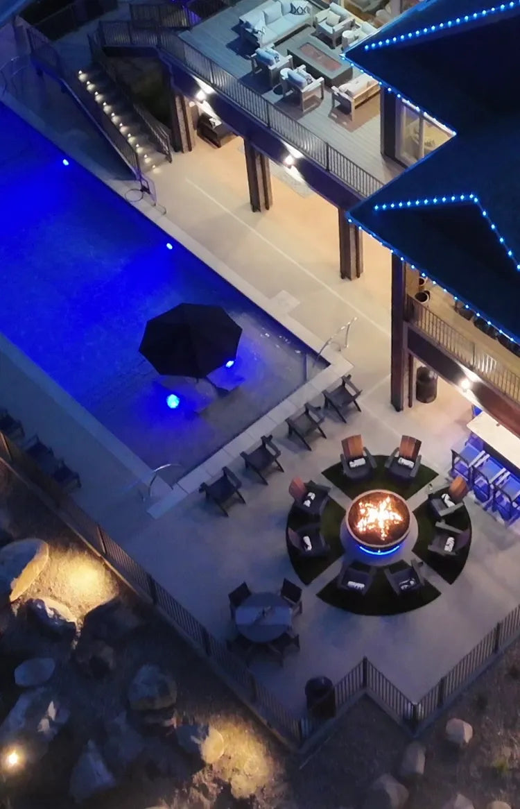 drone aerial footage of a luxury backyard with a large fire pit and blue led lights