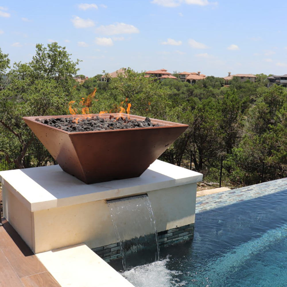 Outdoor fire pit with orange flames, round copper-colored bowl atop a base