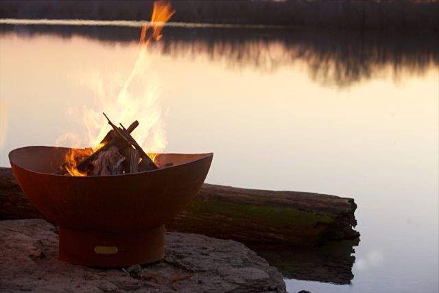Rust wood fire pit with stacked logs and flames inside bowl