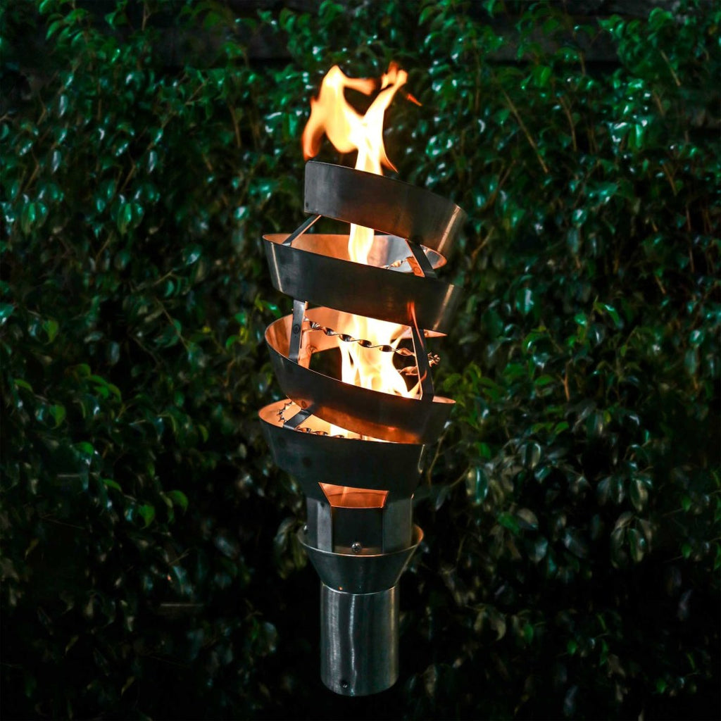 Spiral metal outdoor torch with stand, burning flame inside a dark standing base