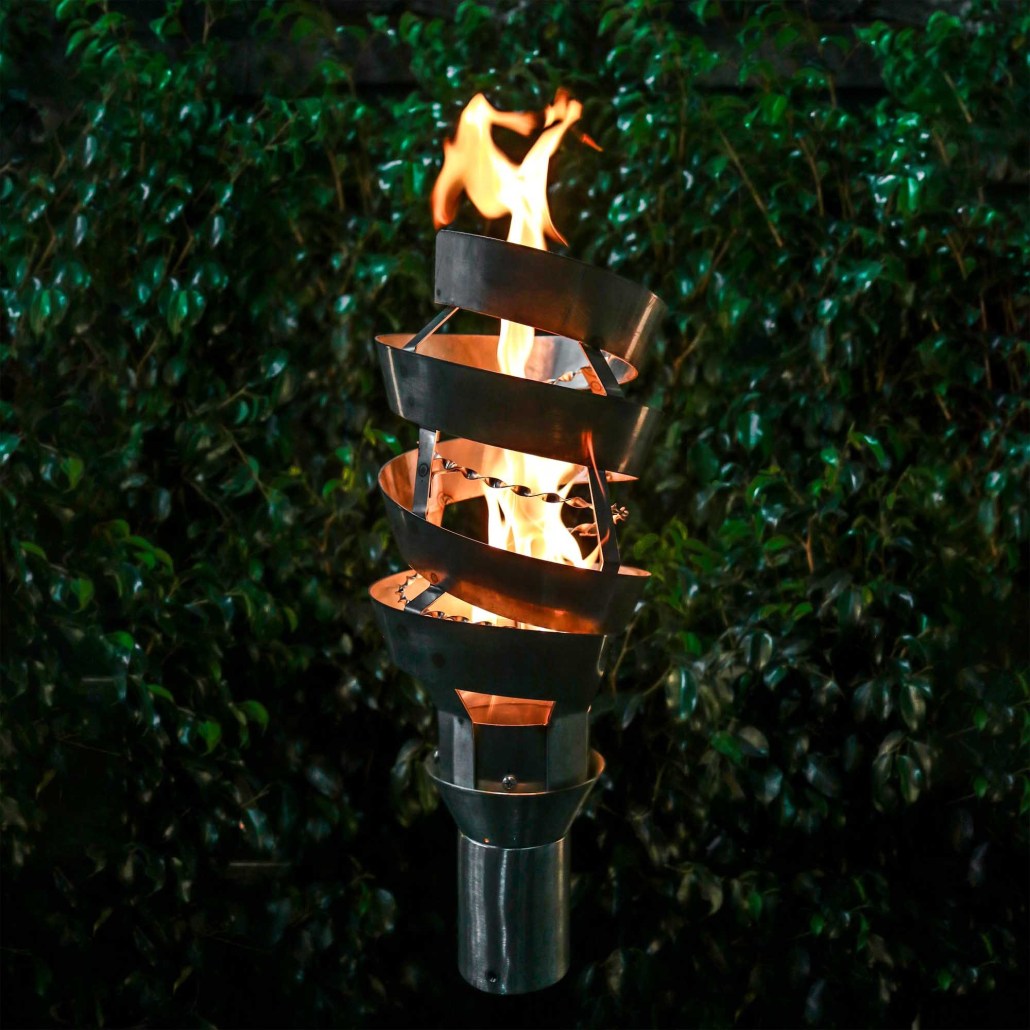 Spiral metal outdoor torch with stand, burning flame inside a dark standing base