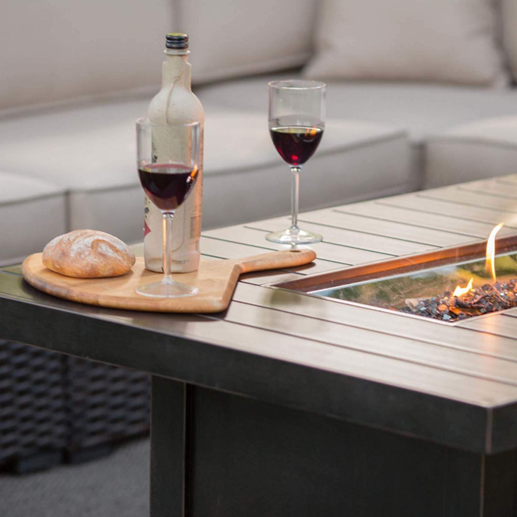 Fire table tabletop with wine glasses and bottle, flames visible at the burner area