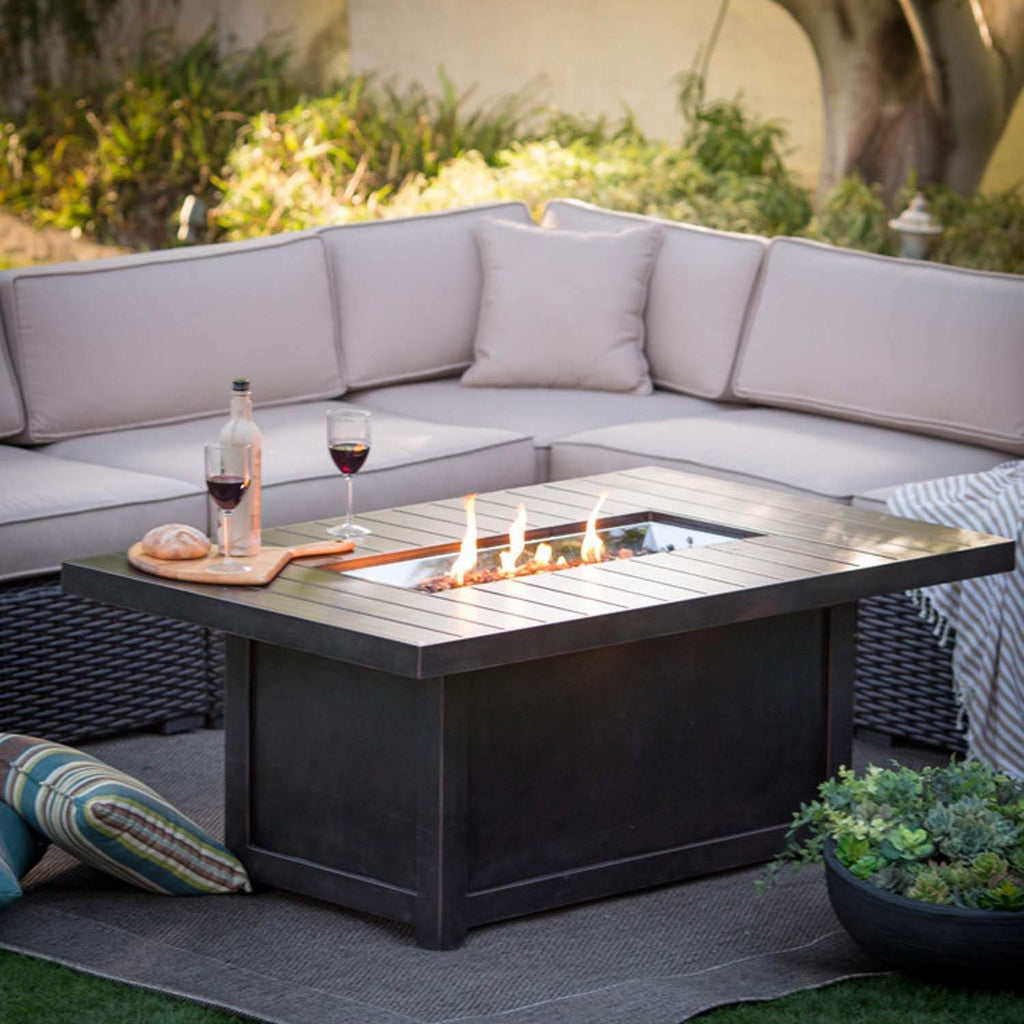 Patio fire table with drinks and bread on the tabletop and flames in the center