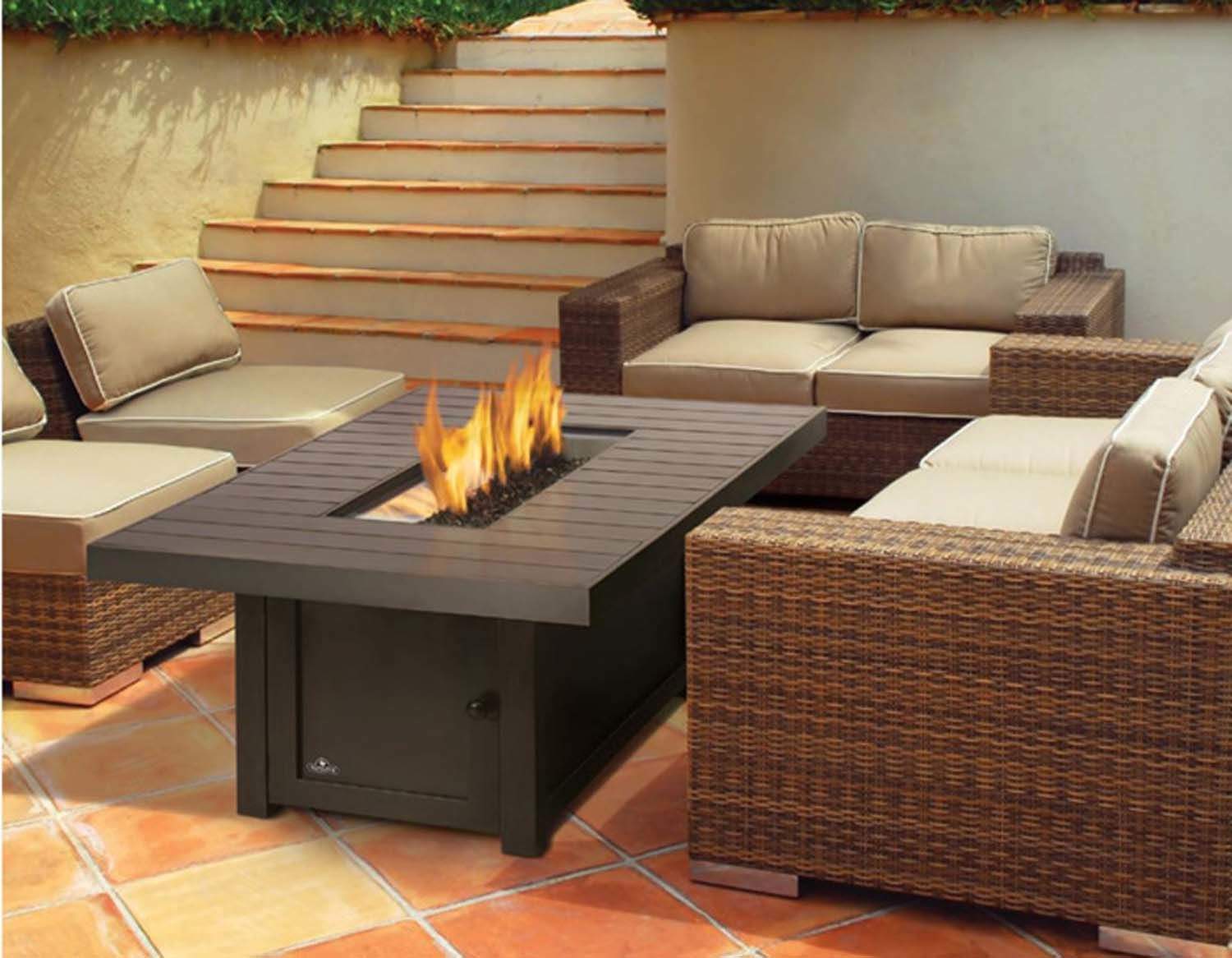 Outdoor fire table with dark tabletop and flames, set within a patio seating area
