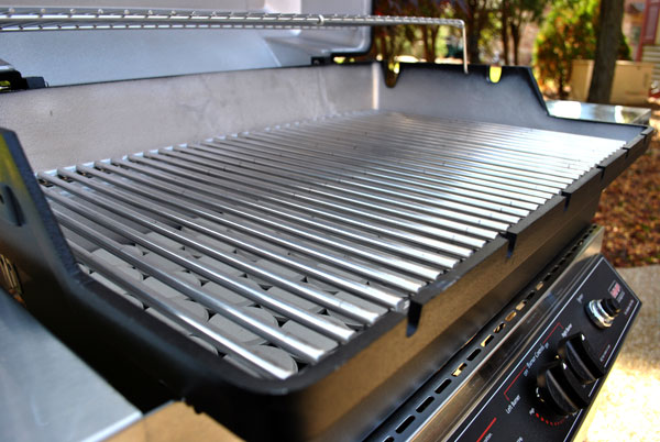 Gas grill with stainless cooking grates and open lid, control knobs on front