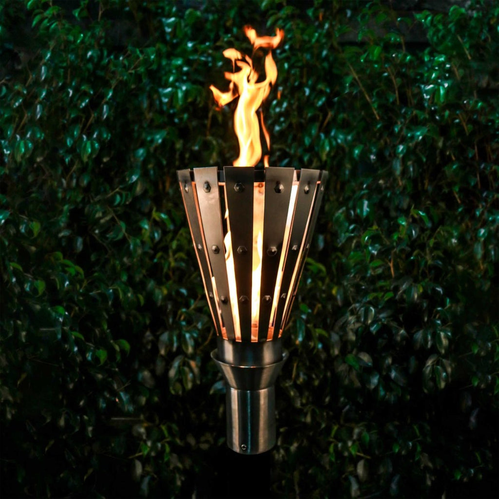 Outdoor flame torch with metal fan-style surround and vertical stand, lit with orange fire