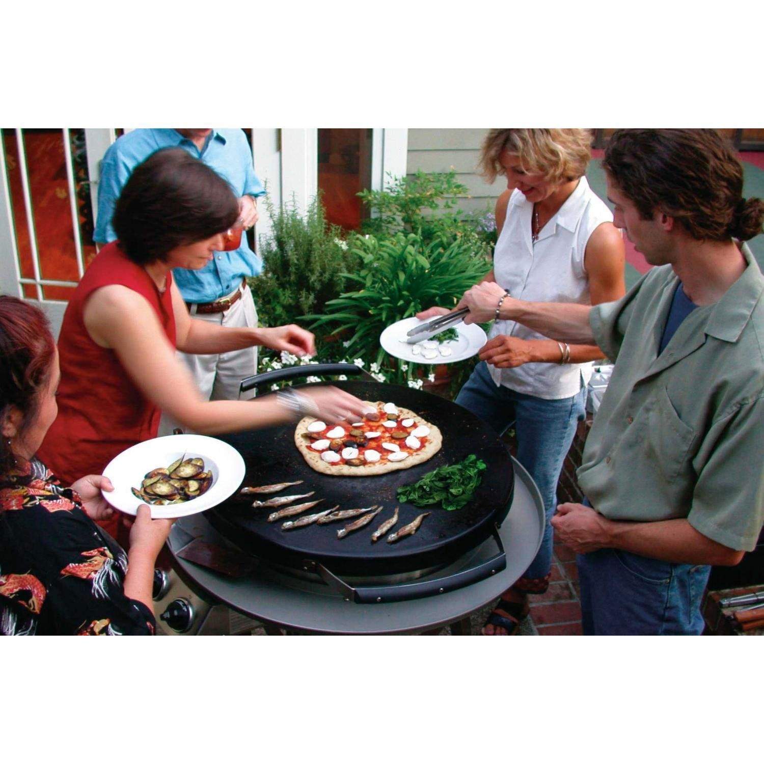 Outdoor gathering cooking on a round gas grill on a wheeled cart